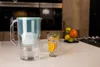 A water filter pitcher and a glass of water with orange slices and mint are on a kitchen counter. Náhľad obrázku produktu