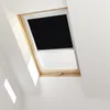 A black blackout roller blind is partially rolled down on a wooden-framed skylight. Produktbild-Vorschau
