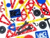 A collection of construction toy parts, including gears, wrenches, wheels, and building pieces, arranged on a white background. Náhľad obrázku produktu