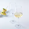 Two wine glasses, one filled with white wine, and two appetizer spoons with food on a white surface. Produktbild-Vorschau