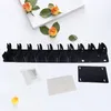 Schwarzer Wand-Organizer mit mehreren Fächern, separate Montageplatte, Klebepad und Befestigungsmaterial auf weißer Fläche Voir les images du produit