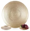 A gold glass dessert plate with a textured, concentric ring pattern is shown against a white background. Two smaller plates and a bunch of grapes are also visible. Podgląd zdjęcia produktu