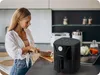 A woman is preparing food in a modern kitchen, with an air fryer prominently displayed on the counter. Anteprima dell’immagine prodotto