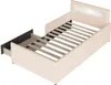 A beige upholstered bed frame with a slatted mattress base and a pull-out drawer. Produktbild-Vorschau