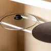 A close-up view of two pot lids on a shelf inside a cabinet. Produktbild-Vorschau