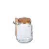 A clear glass jar with a cork lid and a small wooden spoon attached to the side. Anteprima dell’immagine prodotto