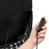 A hand is holding a car charger plug near a 12V DC port on a black object, possibly a car seat. Produktbild-Vorschau