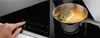 A split image showing a hand interacting with an induction cooktop control panel on the left, and a pot of soup cooking on the right. Podgląd zdjęcia produktu