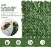 A close-up of a person attaching a panel of artificial ivy to a wire mesh, with marketing text and icons at the bottom. Produktbild-Vorschau