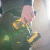 A person holding a yellow and black power drill. Produktbild-Vorschau