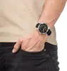 A person's arm and torso are shown, with a watch on the wrist and a hand in the pocket of dark jeans. Produktbild-Vorschau