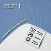 A close-up of a light blue fitted sheet showing its texture and elastic edge, with a care label and text overlays highlighting features. Produktbild-Vorschau