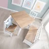 A child's table and chairs set is shown from a top-down perspective in a room with pastel-colored walls and framed artwork. Produktbild-Vorschau