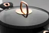 A close-up shot of the lid of a black pot with a copper handle. Náhled obrázku produktu