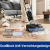 A person is using a wet dry vacuum cleaner on a wooden floor, with a dog lying on a couch in the background. Náhled obrázku produktu