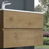 A close-up view of a wooden bathroom vanity with two drawers, with a white faucet and countertop visible. The background shows a garden with trees and bushes. Produktbild-Vorschau