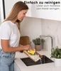 A woman is washing a wooden cutting board in a kitchen sink. Náhled obrázku produktu