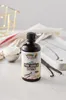 A bottle of vanilla extract is placed on a marble surface with a scoop of cream and vanilla beans nearby. Produktbild-Vorschau