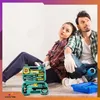 A couple is sitting on the floor next to an open tool kit, looking up. Produktbild-Vorschau