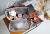 A baby backpack filled with baby items, placed on a table with dried flowers in a vase. Produktbild-Vorschau