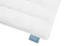 A close-up of a white quilted blanket with a blue tag. Voir les images du produit