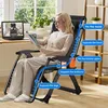 A woman is relaxing in a black zero gravity chair while reading a magazine, with a laptop and plants in the background. Produktbild-Vorschau
