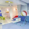 A brightly colored indoor play area for children, featuring a gymnastics bar, a scooter, and seating areas. Voir les images du produit