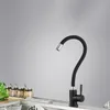 A black kitchen faucet with a flexible hose is shown in a kitchen sink setting. Several spice jars are visible in the background. Náhľad obrázku produktu