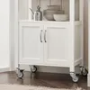 A close-up view of the bottom section of a white kitchen cart, showing its doors and wheels. Produktbild-Vorschau