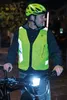 A man wearing a yellow helmet and a high-visibility vest is standing next to a bicycle at night, with the bicycle's headlight on. Náhľad obrázku produktu