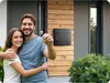 A happy couple holding keys in front of their new home. Produktbild-Vorschau