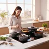 A woman is cooking in a modern kitchen with a set of pots on a stovetop. Náhľad obrázku produktu