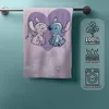 A towel with Lilo and Stitch characters is hanging on a towel rack against a blue wall. A panel with product information is on the right side. Produktbild-Vorschau