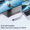 A laptop connected to a USB-C hub, which is also connected to a large monitor, displaying a scenic view. Produktbild-Vorschau