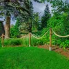 A garden scene with a rope fence and lush greenery. Produktbild-Vorschau