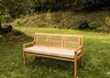 A wooden bench with a beige cushion sits on a grassy lawn in a garden setting. Voir les images du produit