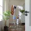 An entryway scene with a coat rack, plant, and chest of drawers. Produktbild-Vorschau
