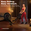 A woman is using a foldable elliptical trainer in a living room. Produktbild-Vorschau