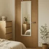 A bedroom scene with a dresser and a mirror hanging on a door. Anteprima dell’immagine prodotto