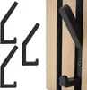A close-up of black metal coat hooks mounted on a wooden panel with black stripes. Produktbild-Vorschau