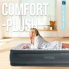 A woman is lying on an Intex air mattress in a bright, modern room. Produktbild-Vorschau