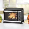 A rotisserie oven with a chicken cooking inside, placed on a countertop with some food items. Náhľad obrázku produktu