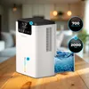 A white dehumidifier is placed on a wooden table in a modern living room setting. Náhled obrázku produktu