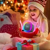 A young girl is excitedly opening a gift on Christmas, revealing a colorful speaker with a wireless charging symbol. Produktbild-Vorschau
