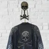 A skull-shaped wall hook with wrenches, holding up a motorcycle jacket. Produktbild-Vorschau