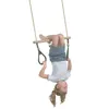 A young girl is hanging upside down from a trapeze swing with green rings. Anteprima dell’immagine prodotto