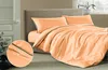 A neatly made bed with apricot-colored bedding and pillows. Produktbild-Vorschau