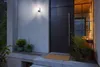 A modern front door with a wall-mounted light and potted plants. Anteprima dell’immagine prodotto