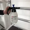 A hand holds a white and black Würth brand pump sprayer with a blue top, positioned against a white background and some metal scaffolding. Produktbild-Vorschau