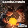 Two children are looking at a glowing yellow ball in a festive setting with Christmas lights. Náhľad obrázku produktu